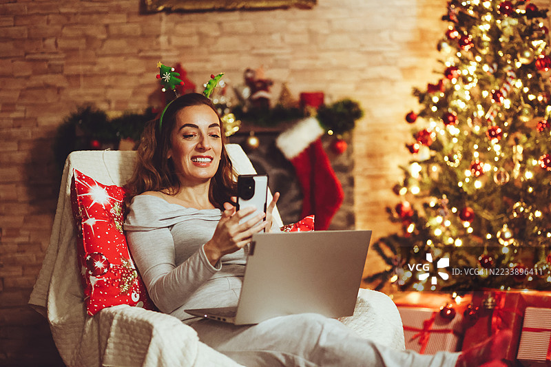 女人在圣诞假期期间使用笔记本电脑和手机图片素材