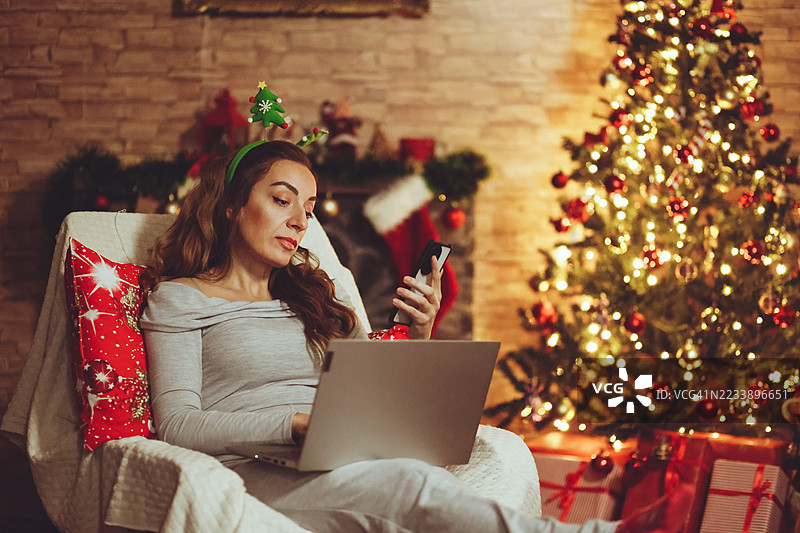女人在圣诞假期期间使用笔记本电脑和手机图片素材