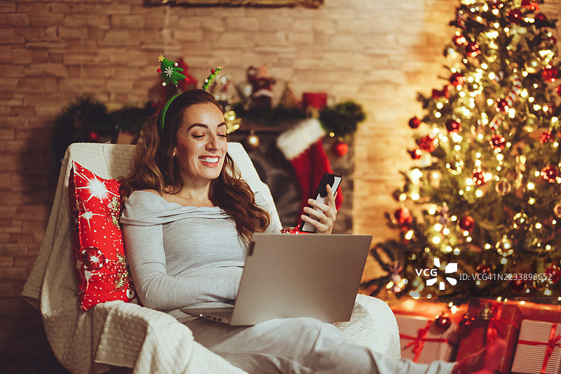 女人在圣诞假期期间使用笔记本电脑和手机图片素材