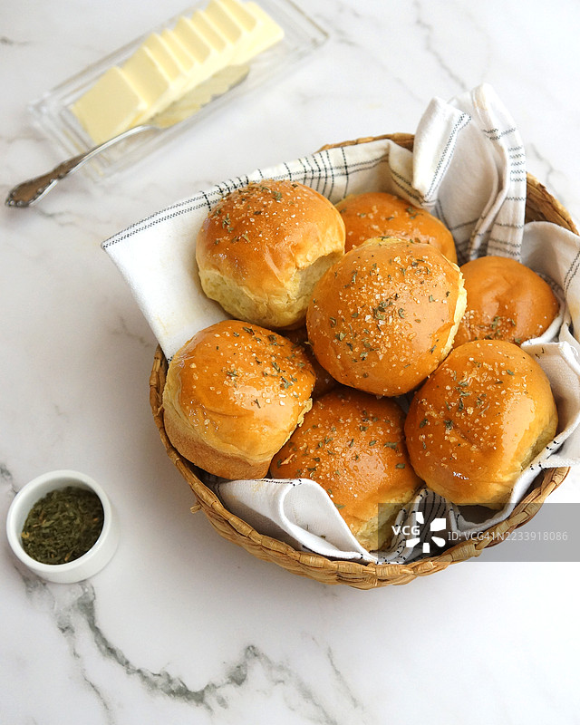 香蒜黄油晚餐卷配香菜和烤蒜，放在面包篮中图片素材