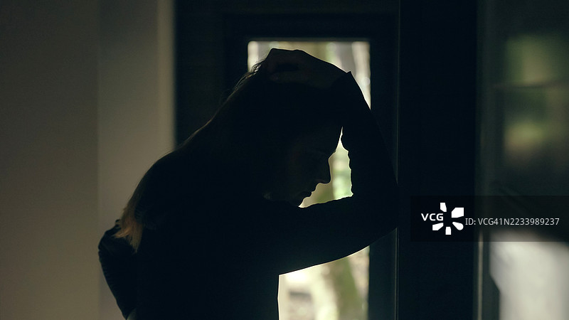 女孩坐在黑暗的房间里，经历心理崩溃——抑郁。图片素材