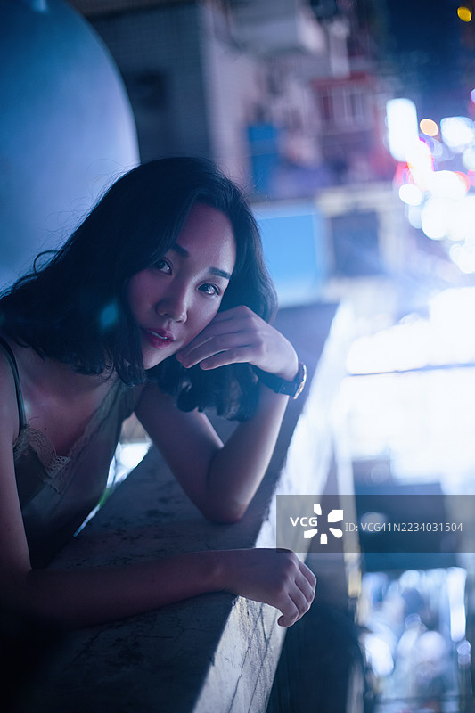 夜晚城市中心霓虹灯下的亚洲年轻女性图片素材