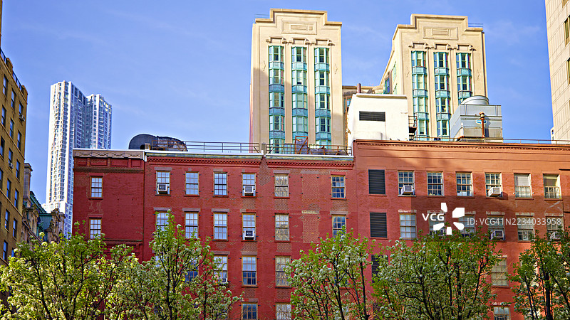 红砖住宅楼，盛开的树木和现代塔楼在背景中，纽约，美国图片素材