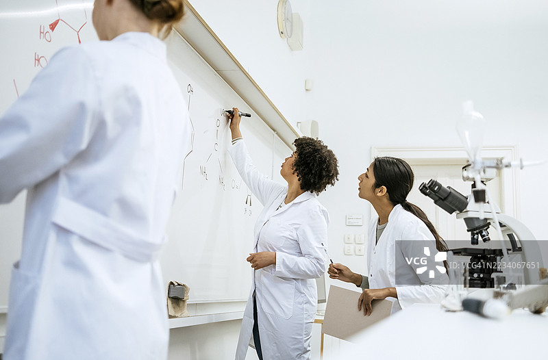 年轻女性科学家在实验室分析化学公式图片素材