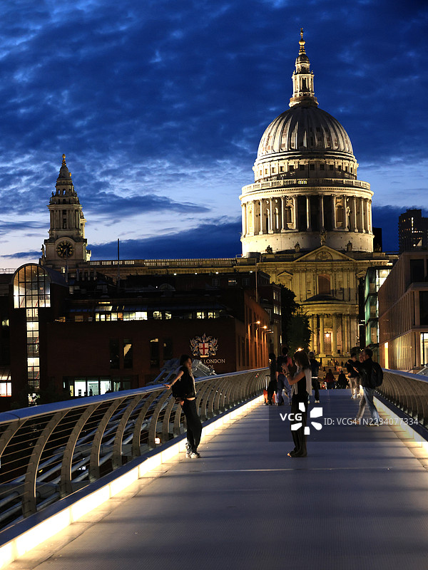 伦敦千年桥上的圣保罗大教堂和人们在夜晚的景象图片素材