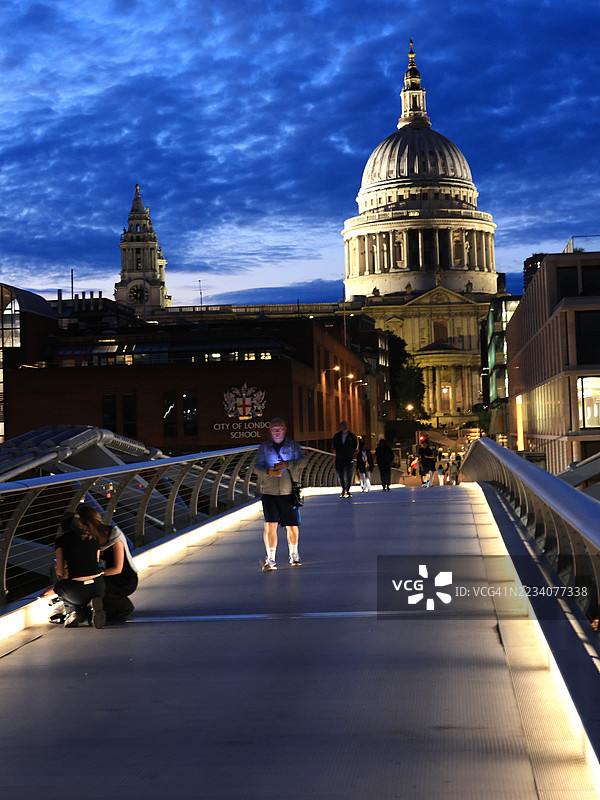 伦敦千年桥上的圣保罗大教堂和人们在夜晚的景象图片素材
