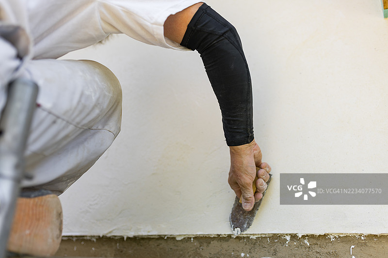 一名抹灰工正在给一栋正在建设中的房屋外墙抹灰。图片素材