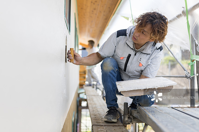 一名抹灰工正在给一栋正在建设中的房屋外墙抹灰。图片素材