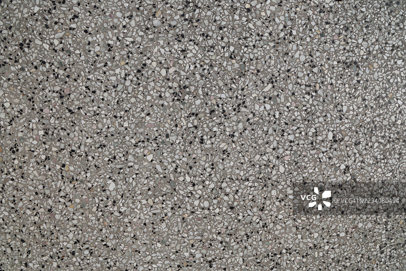 灰色背景的水磨石，嵌入了许多不规则形状、不同大小和颜色的碎片，主要是白色、黑色，以及微妙的粉色或浅灰色。图片素材