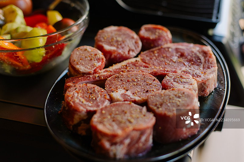 新鲜蔬菜和调味生牛排切块的特写镜头，适合烧烤图片素材