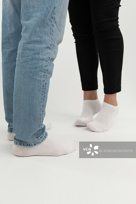 一对情侣穿着袜子站在一起，背景为白色。图片素材