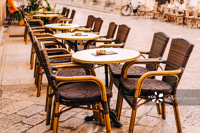 阳光明媚的日子里，户外咖啡馆的空桌子和座位图片素材