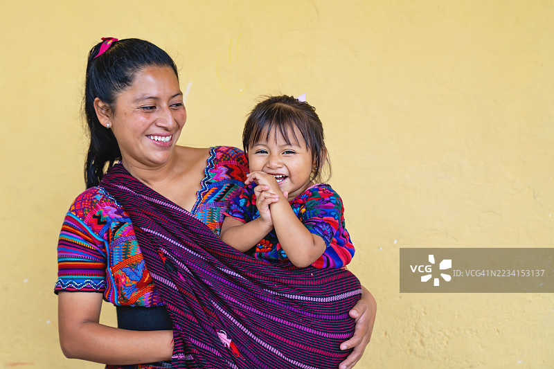微笑的玛雅母亲抱着穿着传统服装的女儿图片素材