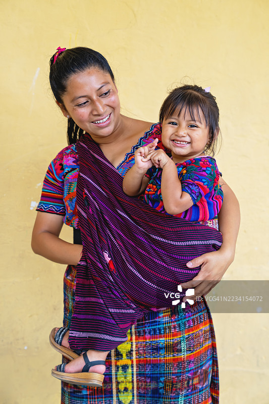 微笑的玛雅母亲抱着穿着传统服装的女儿图片素材