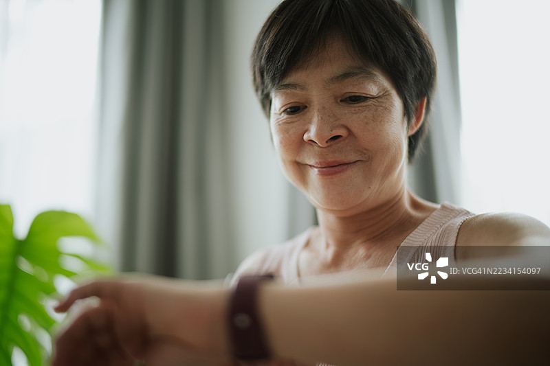 成熟的女性在锻炼时查看智能手表上的健身追踪器。图片素材