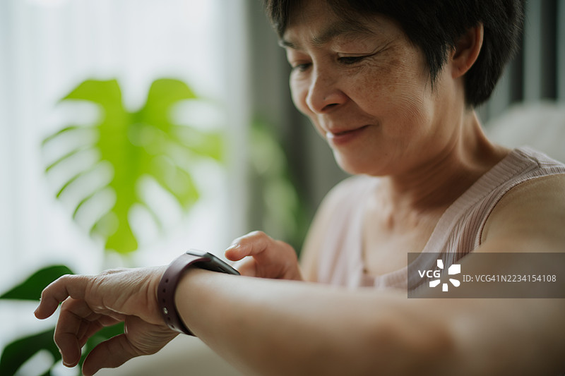 成熟的女性在锻炼时查看智能手表上的健身追踪器。图片素材