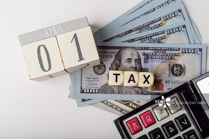 四月一日的税季准备，桌上有钱、计算器和日历。图片素材