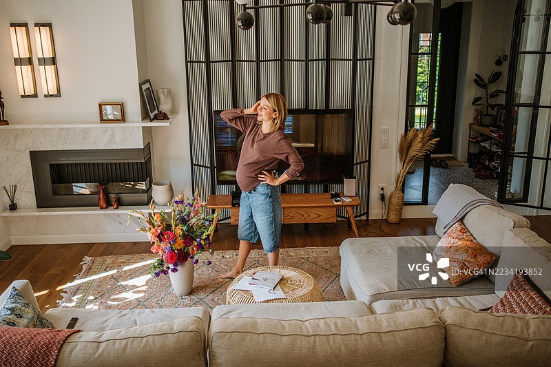 放松的孕妇在家休息，周围鲜花环绕，一切井井有条。图片素材
