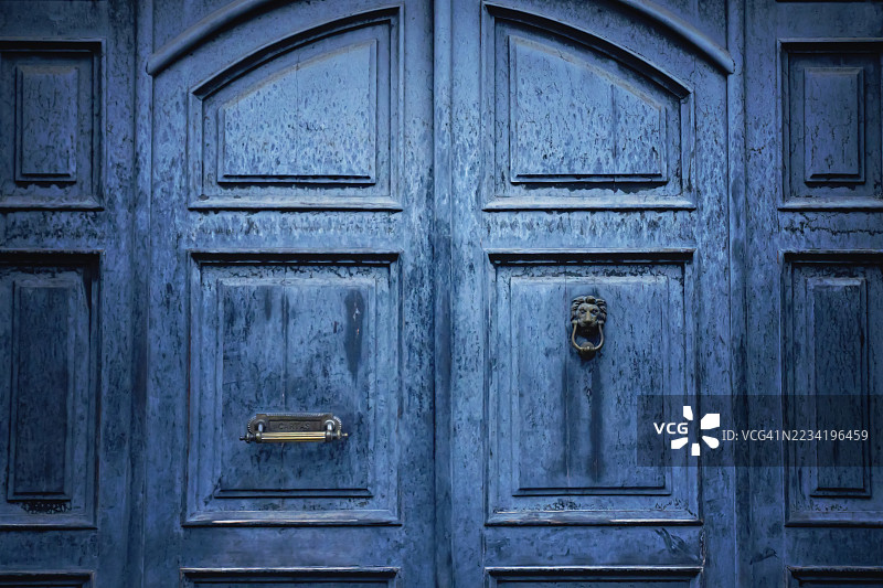 风化的蓝色木门配有狮子形状的门环图片素材