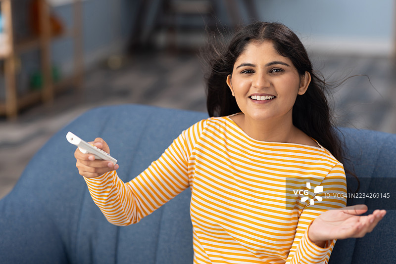 快乐的年轻女性在时尚的家中调节空调，享受阳光明媚的室内舒适与放松时光图片素材