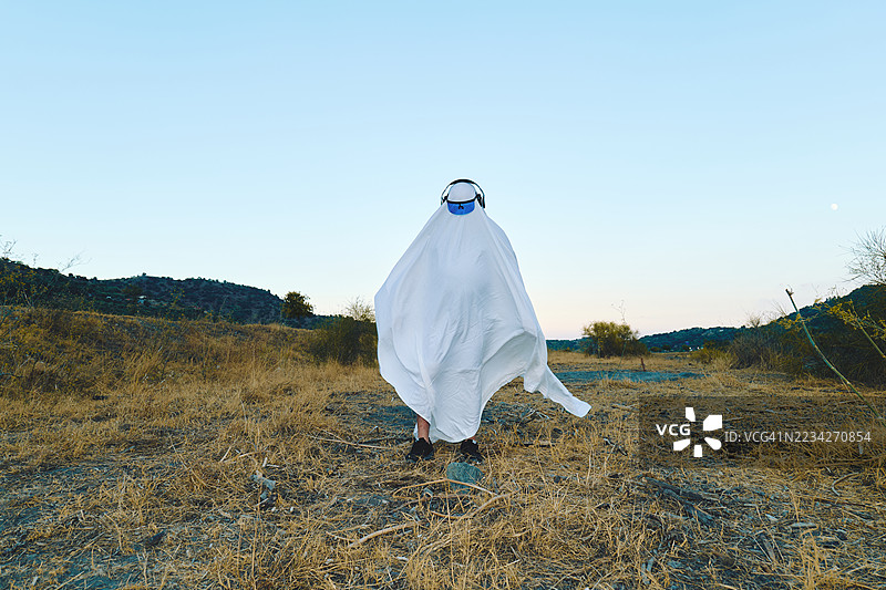 穿着白色床单的鬼魂服装的人在秋季田野小路上图片素材