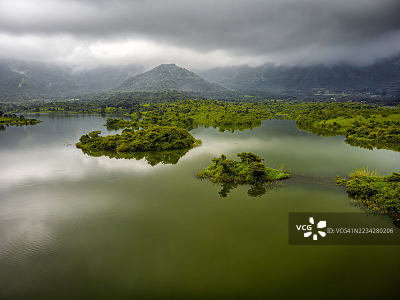 西高止山脉 - 水资源丰富——位于马哈拉施特拉邦拉伊加德区潘维尔的莫尔比村的天然水库/大坝，在美丽的山丘、绿色森林和云朵的衬托下，在季风期间溢出。图片素材