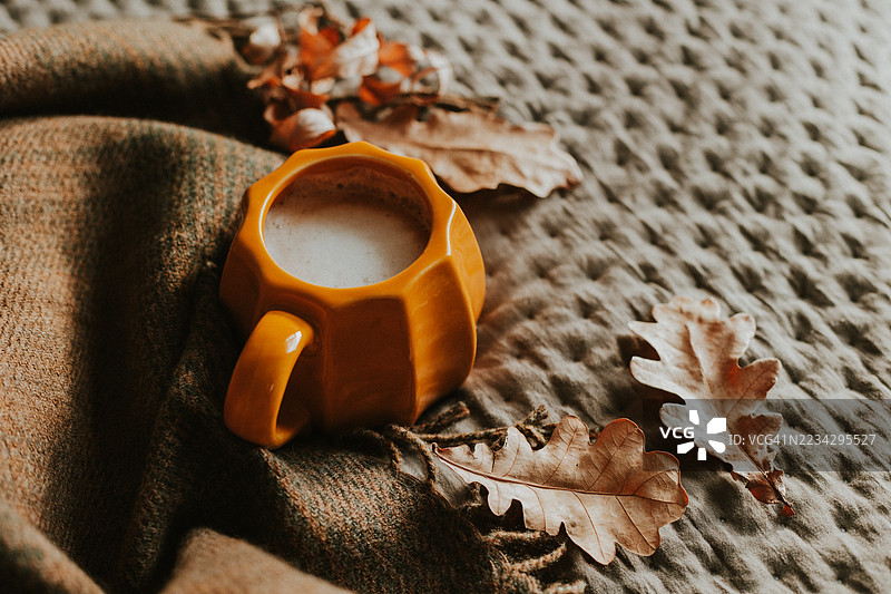 温暖的秋季饮品，盛在黄色杯子里，搭配季节装饰和舒适的质感图片素材