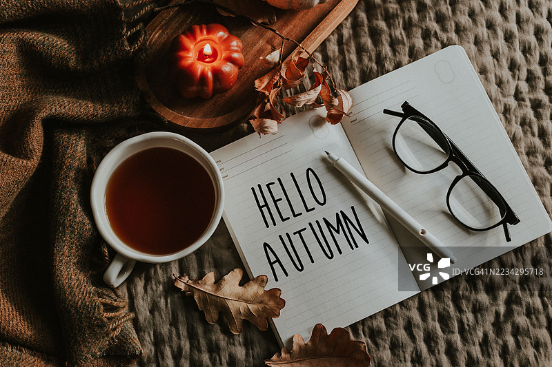 温馨的秋季场景，配有茶、笔记本和季节性装饰图片素材