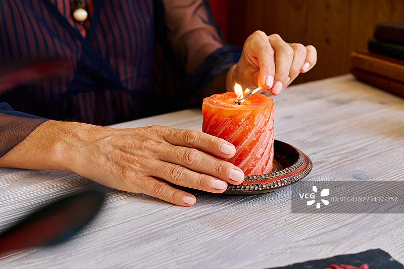 无法辨认的女性点燃蜡烛。温馨的秋季氛围。图片素材