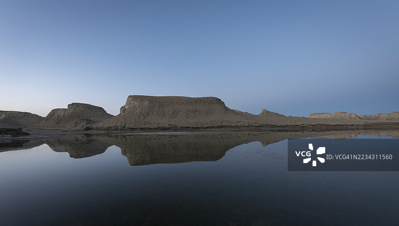 戈壁沙漠中的雅丹地貌在黄昏时分映照在湖面上。图片素材