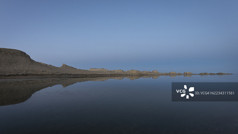 戈壁沙漠中的雅丹地貌在黄昏时分映照在湖面上。图片素材