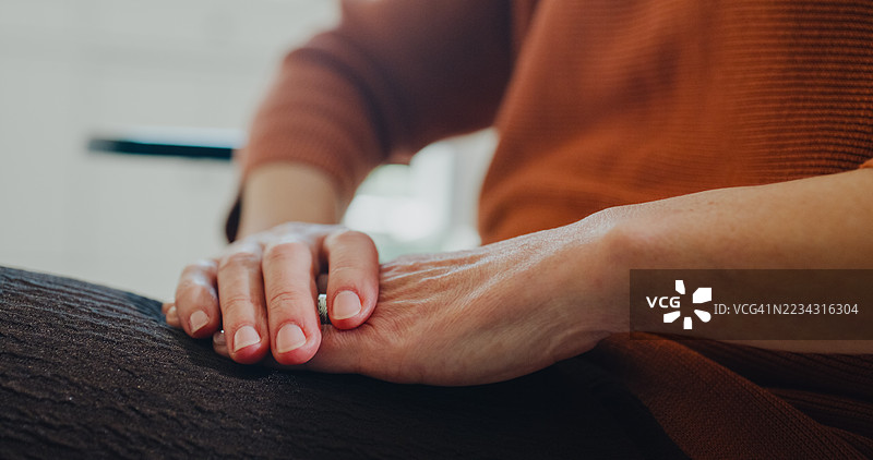 戴头巾的老年女性癌症患者独自坐在家中客厅的沙发上思考。与癌症共存的概念。图片素材