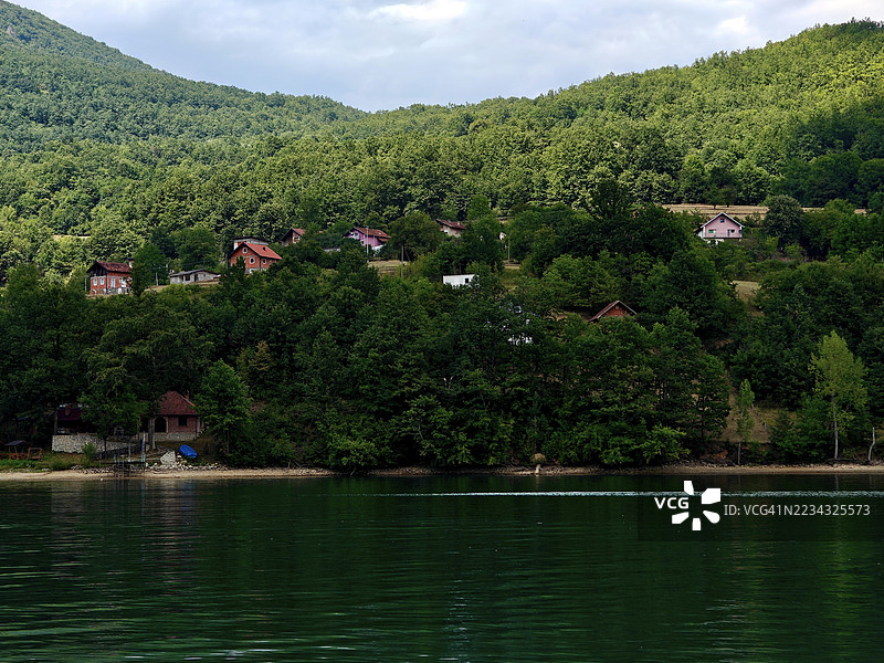 宁静的湖泊被森林山丘和房屋环绕，斯雷布雷尼察，波斯尼亚和黑塞哥维那图片素材