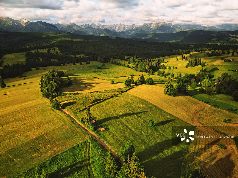 波兰的郁郁葱葱的农业田野鸟瞰图，背景是山脉。图片素材