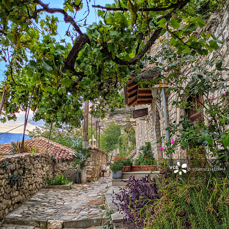 风景如画的石头小径，周围是郁郁葱葱的绿植，位于阿尔巴尼亚的贝拉特乡村图片素材