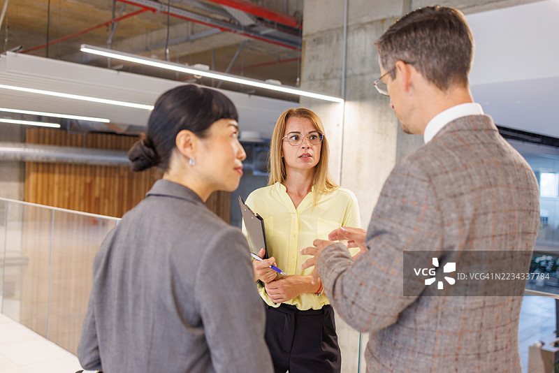 商务人士在办公室走廊进行非正式会议交谈图片素材
