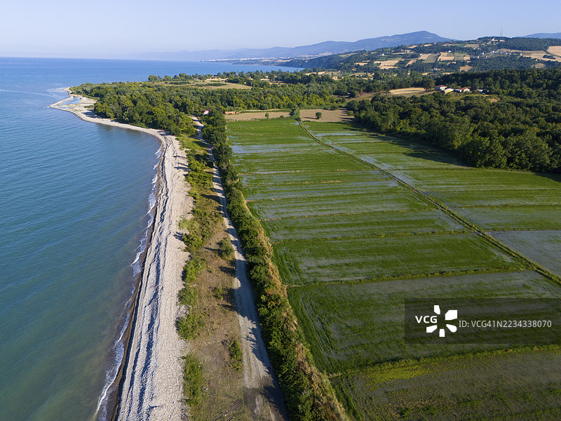 海岸线和邻近的绿色田野与蓝色海洋相接，背景是起伏的山丘，鸟瞰图，位于土耳其萨姆松省的Sancaklı附近的稻田图片素材