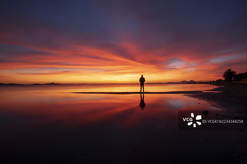 日落时分，站在海滩上的男人剪影，西班牙卡塔赫纳，马尔梅诺尔图片素材
