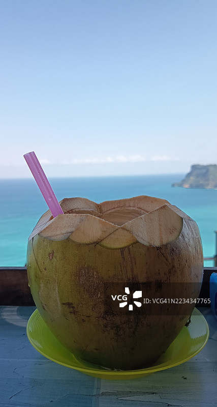 新鲜椰子配吸管，桌子上俯瞰海洋图片素材
