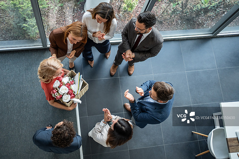 经理们祝贺即将离职的员工，手里拿着鲜花和礼物图片素材