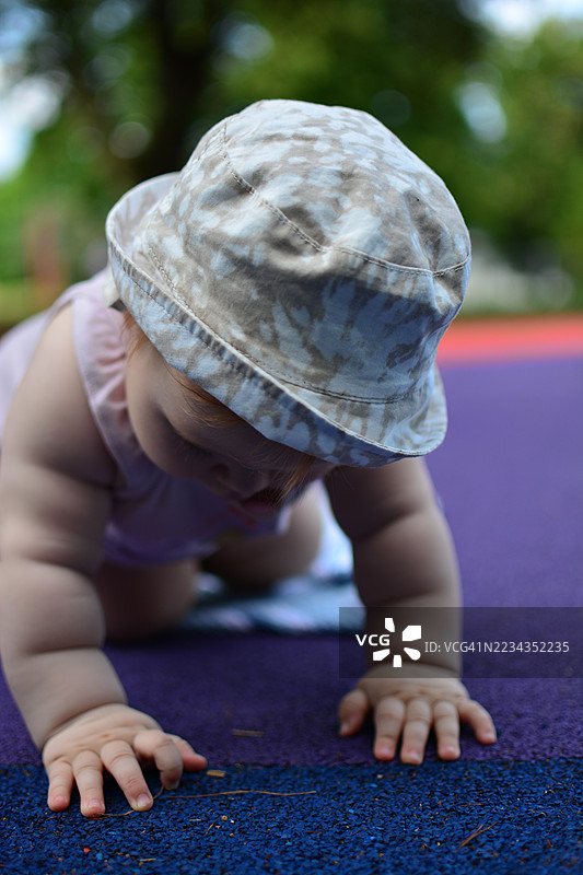一个女婴在色彩鲜艳的户外地面上爬行图片素材