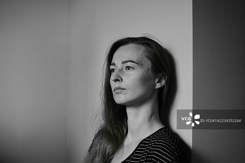一位年轻女子黑白肖像，站立在墙边图片素材