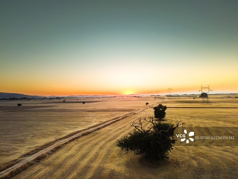 日落时分，广阔的农田与电力线相映成趣图片素材