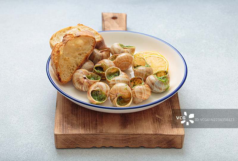 蒜蓉黄油蜗牛配烤面包放在盘子里图片素材