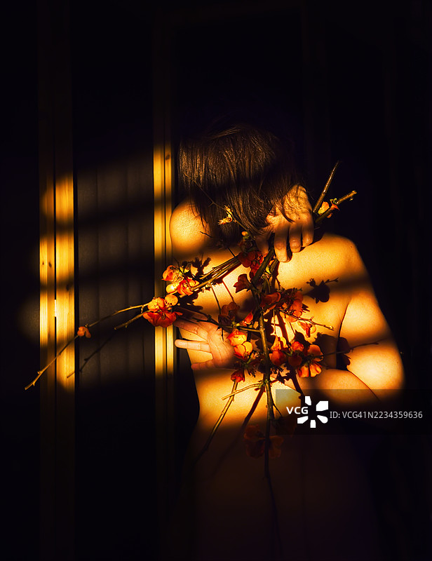 一位女士在戏剧性的光线下拿着一束花图片素材