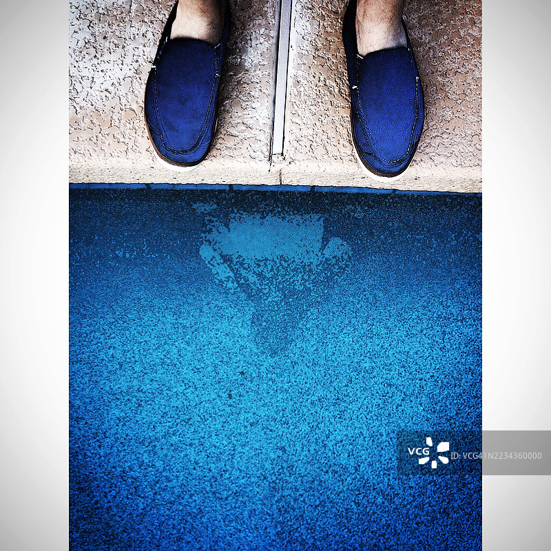 一个人站在泳池边，水中映出他的身影图片素材