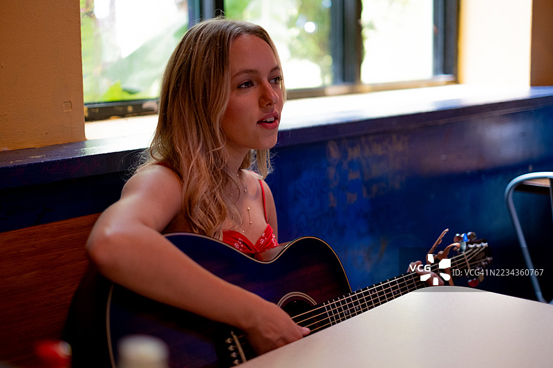 一位女士在舒适的室内环境中弹吉他图片素材