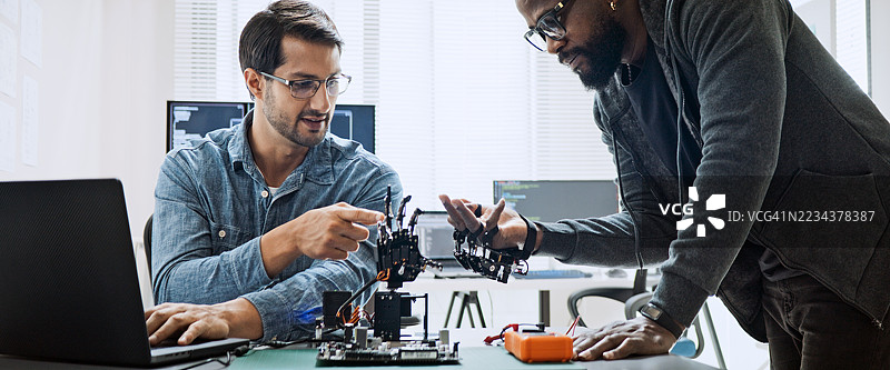 黑白男性软件开发程序员一起在机器人手臂机器上进行编码，使用计算机控制的机器人手臂电路。编程语言，硬件开发技术概念图片素材