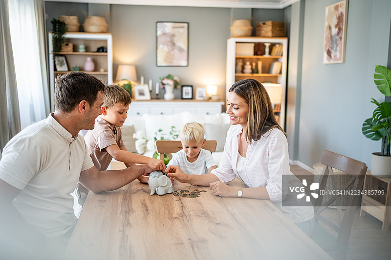 家庭在家一起存钱，把硬币放进储蓄罐里图片素材