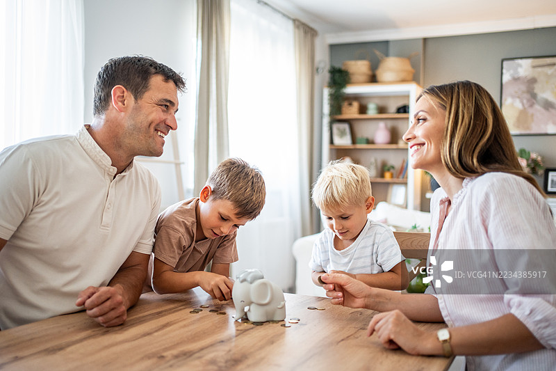 快乐的家庭在家一起存钱图片素材